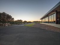 a parking lot with an empty car park with trees and grass around it at sunset