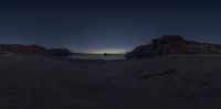 the sun sets on an empty beach with waves crashing toward the rocks, with two small boats out on the water