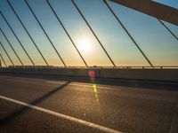 the sun is setting on an overhang of a bridge with a line of lines in the foreground