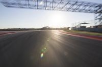 the sun is setting on a race track with a blurry view of a man's car and motorcycle in the motion