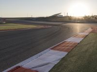 the setting sun casts its rays on a race track with the grass in between the track lanes