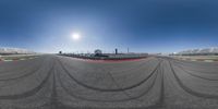 the sun is setting on the track at an airport and a motorcyclist drives along