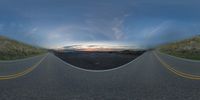 a fish eye lens view of an empty road at sunset with mountains and sky in the background