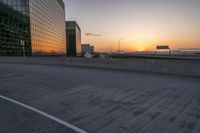 a lone empty road in a deserted city during sunset, with buildings and a sky scrape