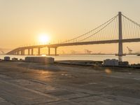 the sun sets over a large bridge in the background with a man running down the road