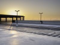 there is an empty parking lot in front of a building at sunset on the seawall