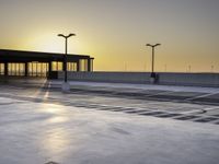 there is an empty parking lot in front of a building at sunset on the seawall