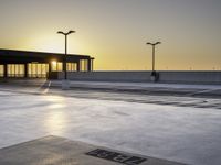 there is an empty parking lot in front of a building at sunset on the seawall