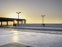 there is an empty parking lot in front of a building at sunset on the seawall