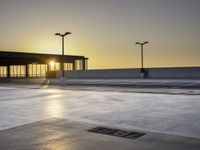 there is an empty parking lot in front of a building at sunset on the seawall