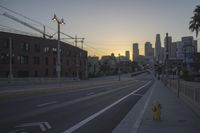 an empty highway with power lines leading to city buildings in the back ground and road tracks