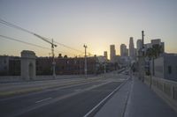 an empty highway with power lines leading to city buildings in the back ground and road tracks