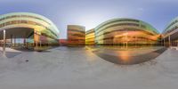 360 view photograph taken in the sunset on a skate board park ramp surrounded by multicolored building and sky