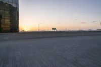 a person riding a skate board across a bridge at sunset in the city with traffic