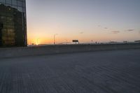 a person riding a skate board across a bridge at sunset in the city with traffic