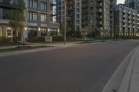 a person riding on a skate board at sunset in an urban street area by some tall buildings