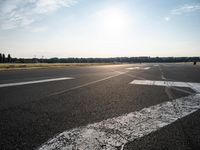 an airplane taking off from a small airport runway at sunset and sun shining down on it