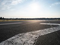 an airplane taking off from a small airport runway at sunset and sun shining down on it