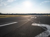 an airplane taking off from a small airport runway at sunset and sun shining down on it