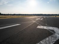 an airplane taking off from a small airport runway at sunset and sun shining down on it