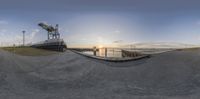 a 360 view of the sunset on a small dock near a body of water with water and power lines behind