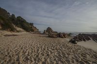 an empty sandy beach with rocks and grass on the beach at sunset in southern california