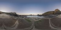 the view from an image of a stone structure in the sand at sunset with rocky shore behind