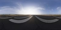 a wide angle view of an airport runway with the sun setting behind it and people standing on the tarmac