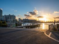 a pier with boats on water during sunset time in the cityscape area of florida