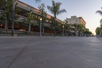 the sun sets over the parking lot at the university of san diego at dusk, overlooking the building's roof and sidewalk