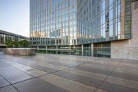 there is a large glass building near the sidewalk and sidewalk area at sunset time,