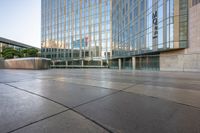 there is a large glass building near the sidewalk and sidewalk area at sunset time,