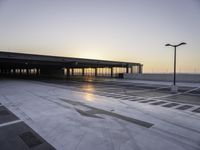 a parking lot that has a sky view at sunset behind it with parking spots near the side