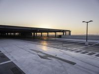 a parking lot that has a sky view at sunset behind it with parking spots near the side