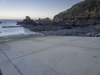 there is a view of the beach from a parking spot at sunset time, the beach has small rocky rocks all around it