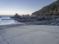 there is a view of the beach from a parking spot at sunset time, the beach has small rocky rocks all around it