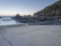 there is a view of the beach from a parking spot at sunset time, the beach has small rocky rocks all around it