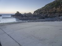 there is a view of the beach from a parking spot at sunset time, the beach has small rocky rocks all around it