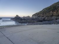 there is a view of the beach from a parking spot at sunset time, the beach has small rocky rocks all around it