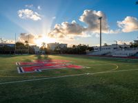 a view of the football field at sunset as the sun shines behind the field