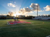 a view of the football field at sunset as the sun shines behind the field