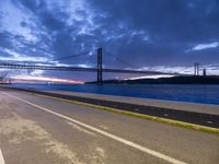 view across the highway of large bridge, a large body of water and a long bridge at sunset