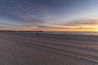 a view of the beach with footprints and the pier at sunset's end with the ocean