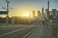 an empty highway with power lines leading to city buildings in the back ground and road tracks