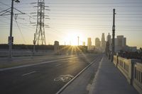 an empty highway with power lines leading to city buildings in the back ground and road tracks