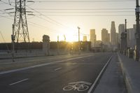 an empty highway with power lines leading to city buildings in the back ground and road tracks