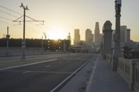 an empty highway with power lines leading to city buildings in the back ground and road tracks