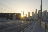 an empty highway with power lines leading to city buildings in the back ground and road tracks