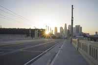 an empty highway with power lines leading to city buildings in the back ground and road tracks