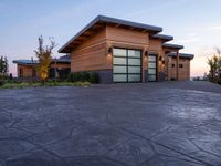 a large wooden home with driveway leading up to the garage entrance at sunset with blue skies